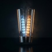 Vela de cristal partida por la mitad que revela dentro una escalera de celdas luminosas, azules por un lado y ámbar por el otro, concepto de vela bid/ask