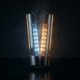 Candela di vetro spaccata a metà che rivela dentro di sé una scala di celle luminose, azzurre da un lato e ambra dall'altro, concetto di candela bid/ask
